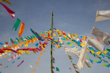 Renkli flamalar sallanan, rüzgarda sallanan, arka planda mavi bir gökyüzü olan bir dizi ip. Kare dansı ve Festa Junina için dekorasyon -
