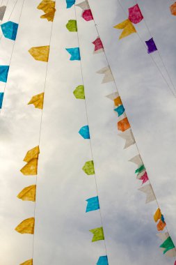 Arka planda bulutlu bir gökyüzü ile asılı renkli flama ipleri. Kare dansı için dekorasyon - tipik bir Brezilyalı partisi.