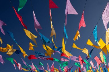  Arkaplanda mavi gökyüzü olan, ipten sallanan renkli flamaları kapat.