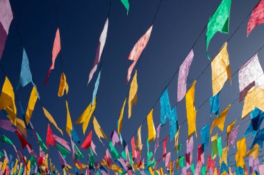 Arkaplanda mavi gökyüzü olan, ipten sallanan renkli flamaları kapat.