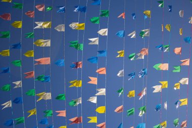 Renkli flamalarla asılı çamaşır iplerinin fotoğrafı, rüzgarda sallanan arka planda mavi gökyüzü. Haziran festivali için dekorasyon.