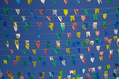  Üzerinde renkli flamalar asılı birkaç çamaşır ipinin panoramik fotoğrafı, rüzgarda sallanan arka planda mavi gökyüzü. Kare dansı.