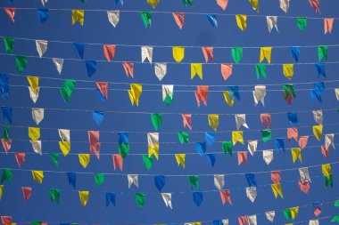  Üzerinde renkli flamalar asılı birkaç çamaşır ipinin panoramik fotoğrafı, rüzgarda sallanan arka planda mavi gökyüzü. Kare dansı.