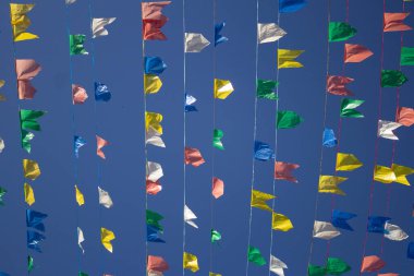 Mavi gökyüzü ve rüzgarda sallanan bir kaç renkli bayraklar. Haziran festivali.