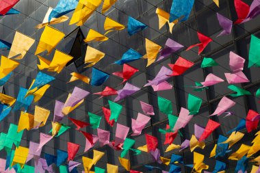  Renkli flamalar arka planda bulanık bir binanın pencereleriyle rüzgarda dans ediyor..