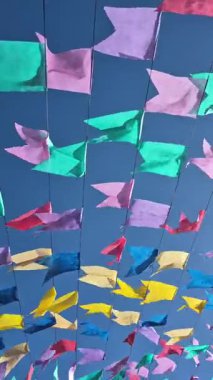 Renkli flamaların videosu, dizelerde asılı, rüzgarda sallanan, arka planda mavi bir gökyüzü.