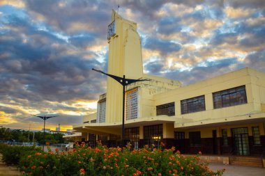 Eski Goiania Şehir Tren İstasyonu 'nun tarihi mimarisi, şimdi Frei Confaloni Müzesi, alacakaranlıkta, ön planda bir çiçek bahçesi ile.