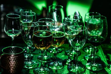 Partide barın tezgahında birikmiş, içinde yeşil ışık olan bir kaç bardak..
