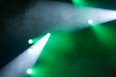 Karanlık bir odayı aydınlatan yeşil ve beyaz ışık demetleriyle sahne ışıkları..