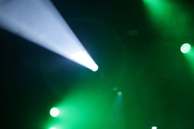 Karanlık bir odayı aydınlatan yeşil ve beyaz ışık demetleriyle sahne ışıkları..