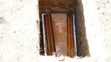 Burial. Men lower the coffin into the grave. n