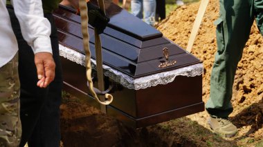 Burial. Men lower the coffin into the grave. n