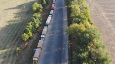 Tahıl teslimi. Hava görüntüsü. Tahıl deposu. Tahıl kamyonları tahıl ambarına giden yolda ayakta duruyor. Trafikte kamyonlar. Hasat ve ürün teslimatı. Tarım endüstrisi. Ağırlığa göre tahıl kamyonları