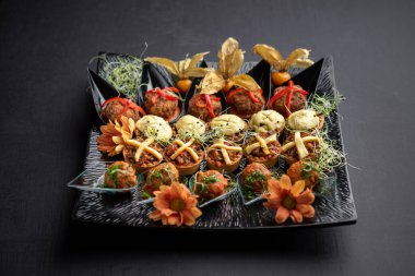 Krem peynirli kanepeler ve çiçeklerle süslenmiş köfteler, kiraz ve mikroyeşil