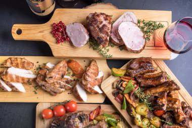 Ahşap tahtalarda servis edilen ızgara, fırın ve kızarmış et çeşitleri. 
