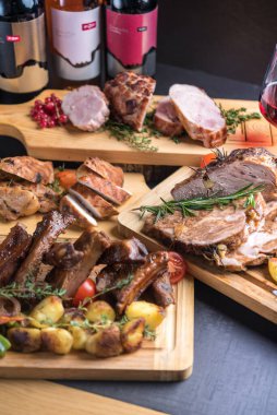 Şarabla servis edilen çeşitli fırınlanmış et ve kızarmış etle birlikte tatil masası.
