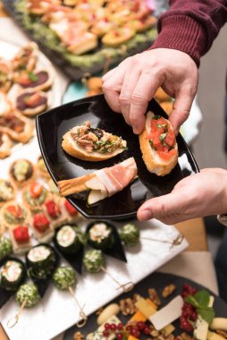 Tabaktaki aperatifleri toplayan adamın detaylı görüntüsü.