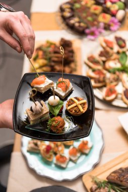 Aperatifleri tabakta toplayan bir adamın görüntüsü.