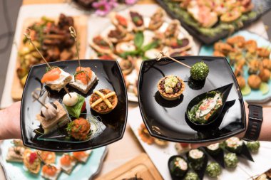 İki adam tabakta aperatifleri topluyor.