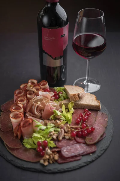 赤ワインのボトルとガラスで提供される硬化肉のプレート — ストック写真
