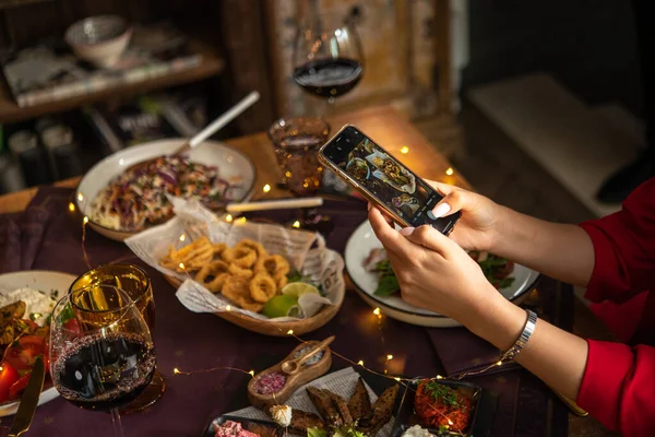 Masada lezzetli yemeklerin fotoğrafını çeken bir kadın.