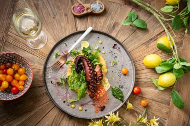 Ahşap masada beyaz şarapla servis edilen ızgara ahtapot.