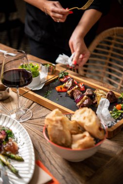 Taş tahtada barbekü servisi yapan kadına yakın çekim.