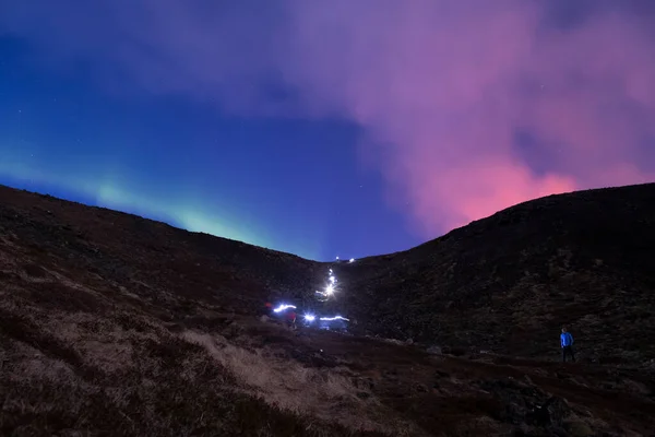 Hiker headlamps long exposure volcano smoke and aurora borealis