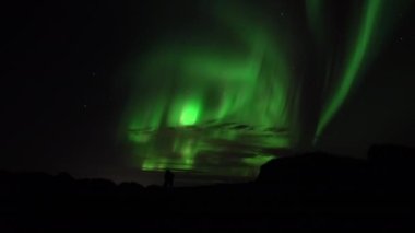 An embracing couple watches aurora borealis real-time video