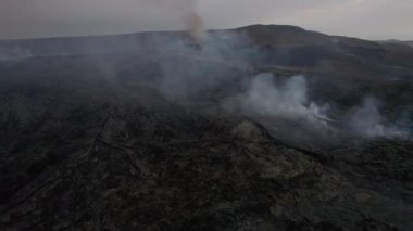 Dumanlı volkanik arazinin üzerinden İzlanda kraterine doğru uçuyor.