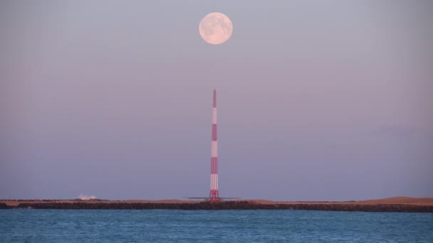 冰岛海滨发射塔上空的满月 — 图库视频影像
