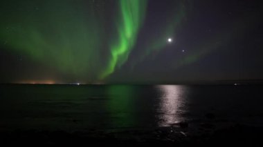 Ay ve Venüs 'ün önündeki okyanusa yansıyan Aurora borealis