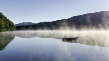 Güneşin doğuşunda sisli atmosferik dağ gölü, ada yüzme limanı
