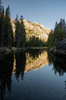 Yosemite 'deki Tuolumne Nehri' nin yavaş akan sularına yansıyan dağlar