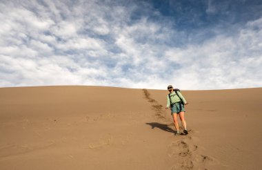 Woman Cautiously Hikes Down Steep Dune in Great Sand DUnes National Park