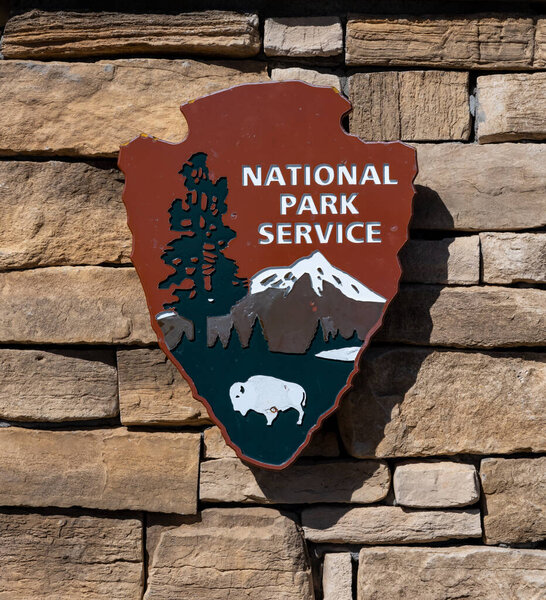 Национальный парк Карлсбадские пещеры, США: знак обслуживания национальных парков, установленный на каменной стене в центре для посетителей Карловых пещер