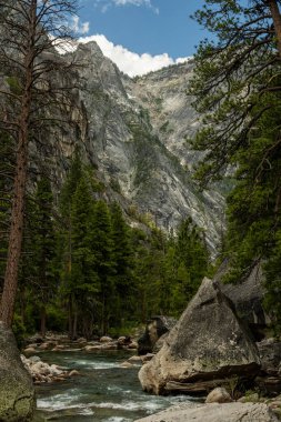 Yosemite Ulusal Parkı 'nın dört bir yanında dik duvarlar bulunan Tuolumne Nehri' nin kıyısında büyük kayalar var.