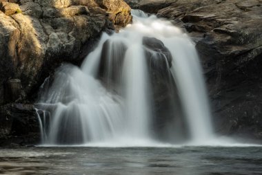 Yosemite 'deki Glen Aulin Yüksek Sierra Kampı' ndaki havuzun etrafındaki Karanlık Kayalıklardan Beyaz Şelaleler akıyor.