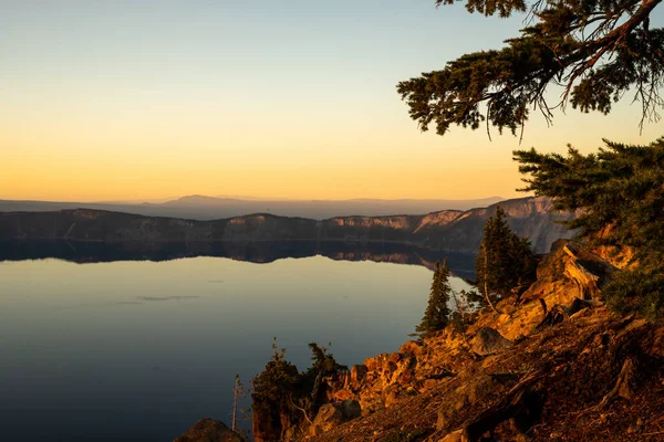 夏の日没時にクレーター湖の上の崖がオレンジに成長します — ストック写真