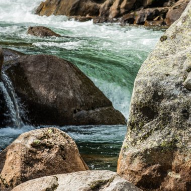 Tuolumne Nehri 'nin temiz suları Yosemite Ulusal Parkı' ndaki başlangıcından itibaren kayaların üzerine yuvarlandı.