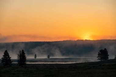 Güneş, Yellowstone Nehri 'nin üzerinde Turuncu Gökyüzünü parlatıyor Yazın devam eden sisle