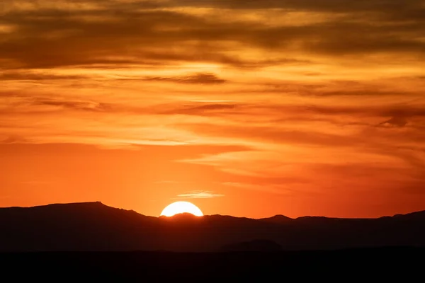Slunce Zapadá Pod Siluetu Hor Proti Oranžové Obloze — Stock fotografie