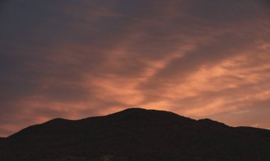 Gökyüzünde pembe renkli bulutlar ve Big Bend Milli Parkı 'nda siluetli tepe kenarları.
