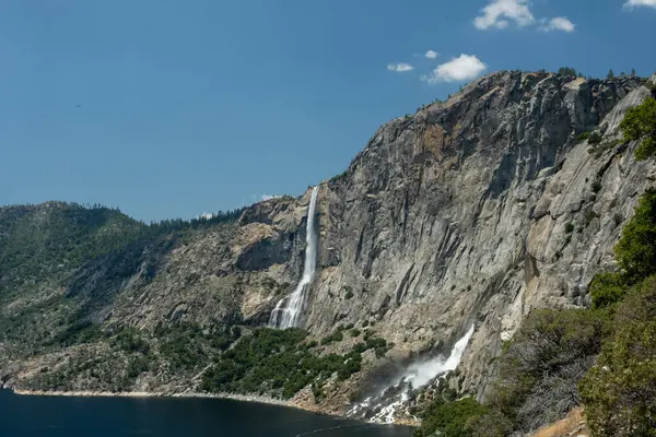 stock image Tueeulala Falls Rushes Down Cliffside into Dark Hetch Hetchy Waters in Yosemite