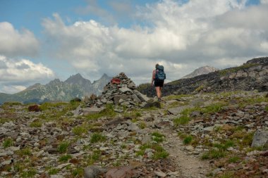 Backpacking Woman Passes Cairn on the Spray Park Trail in Mount Rainier clipart