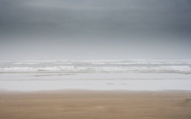 Islak Kum ve Kara Bulutlar Oregon sahilindeki Pasifik Sörf Yapıyor