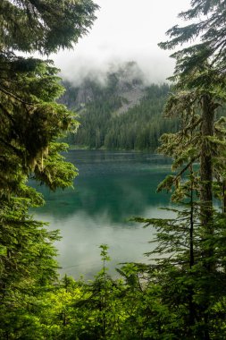 Rainier Dağı Ulusal Parkı 'ndaki Mowich Gölü' nü çevreleyen dağların üzerinde bulutlar dolaşıyor