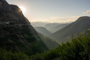 Buzul Ulusal Parkı 'nın aşağısındaki vadiyi aydınlatırken Güneş Işıklarını Top Dağı' nın Gölgelerine Atıyor