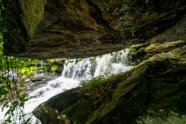 New River Gorge Ulusal Parkı 'ndaki Dunloup Creek' teki şelalede asılı duran bir kayaya bakıyorum.