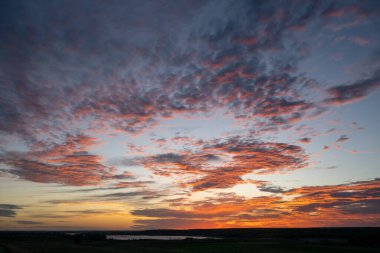 Açık pembe bulutlar Kansas üzerinde güneş doğarken turuncuya dönüşür.
